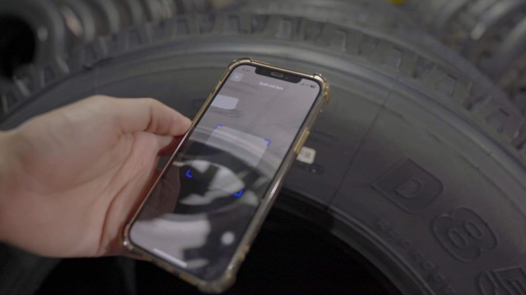 Hình ảnh một người đang dùng điện thoại thông minh để quét mã QR trên tem nhãn của lốp DRC.